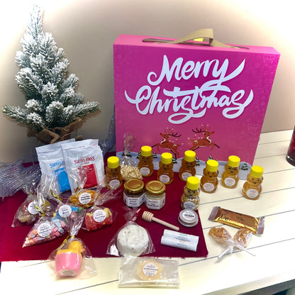 Assorted food items including honey, cookies, and a pink 'Merry Christmas' advent calendar on a table.